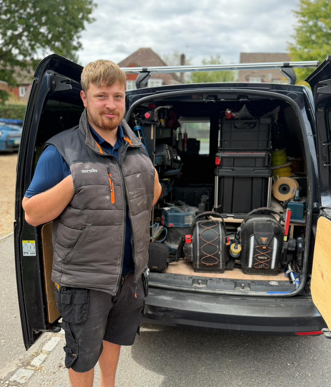 Ollie standing at the back of the Electric Ols van, tools racked behind him